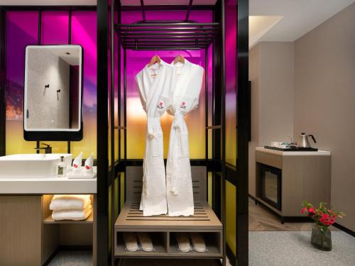 广州宜尚PLUS酒店- 广州珠江新城五羊邨地铁站店的一间带水槽和架子上白色长袍的浴室