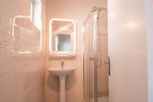 拉戈阿Virginia Guest House的浴室配有盥洗盆和带镜子的淋浴