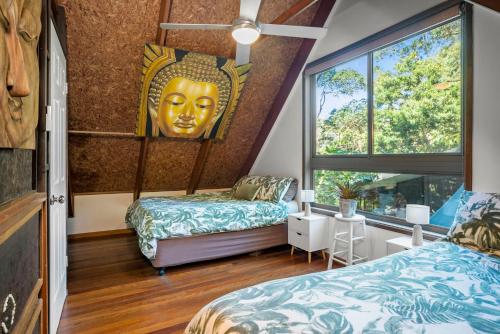 拜伦湾佛陀度假屋的一间设有两张床的房间,墙上有一个巨大的头