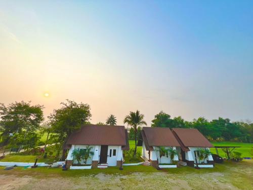 Ban Mae Kham Lang WatThe Green Season Resort的两座房子在田野,背面是日落