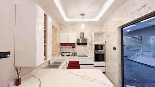 阿克拉Sydney’s villa的一间厨房,配有白色的橱柜和大窗户