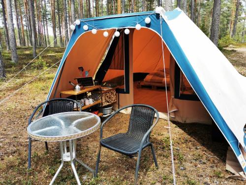 GräsmarkVolledig ingerichte tent op natuurcamping的帐篷前配有桌椅