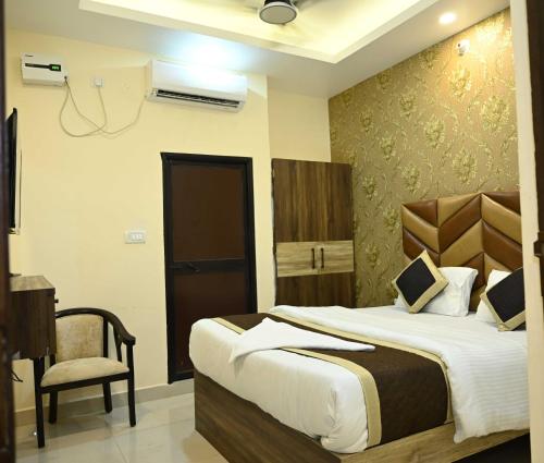 GulzārbāghHotel Glance Inn的一间卧室配有一张大床和一把椅子
