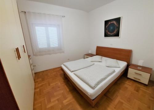 梅杜林Apartments Aurora near beach的一间卧室配有一张带白色床单的床和一扇窗户。