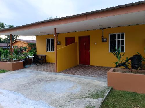 珍南海滩Alfa Roomstay的黄色的房子,有红色的门