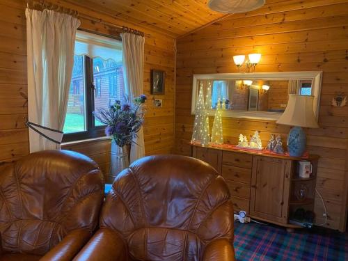 罗厄德南Cozy Cabin with Stunning Loch Lomond Views的客厅配有真皮座椅和镜子