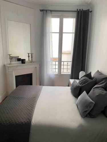 巴黎Charmant appartement cosy 2 pièces Paris 15e的一间卧室设有一张带壁炉和窗户的床。