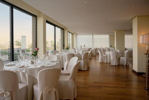 里米尼国家酒店的宴会厅配有白色的桌椅和窗户