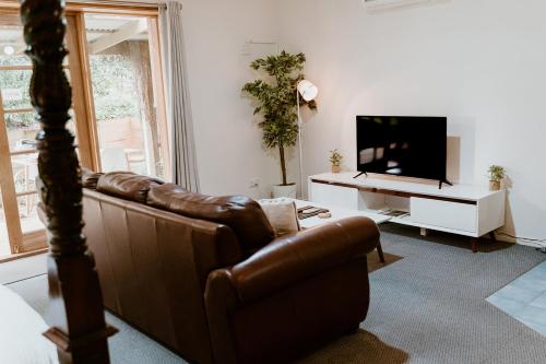 The PatchThe Garden Suite的客厅配有棕色真皮沙发和电视