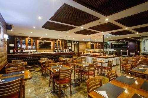 里约热内卢Rio Aeroporto Hotel Galeão的一间带木桌椅的餐厅和一间酒吧