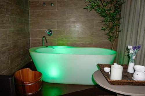 塞蒂拉瓜斯San Diego Suites Veredas Sete Lagoas的设有带绿色浴缸的浴室和桌子