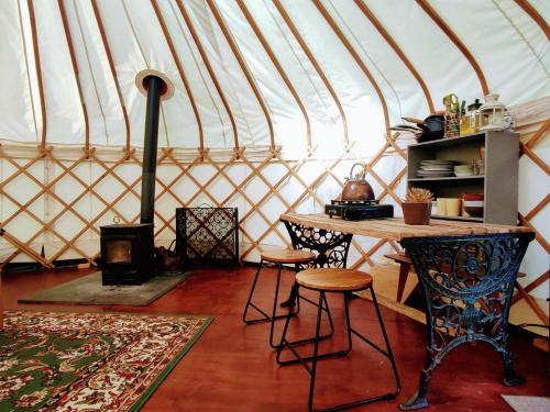 GraffhamBeautiful Yurt with stunning South Downs views的蒙古包内带桌子和凳子的房间