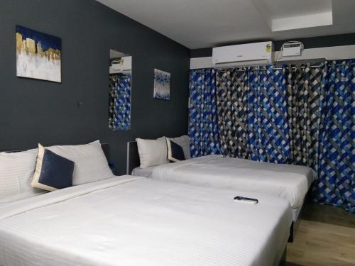 钦奈Silver Cloud Hotel Sholinganallur的配有两张床铺的蓝色和白色窗帘
