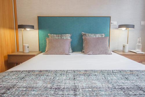 吉马良斯Dom José Alojamentos by Guestify的一间卧室配有一张大床和蓝色床头板