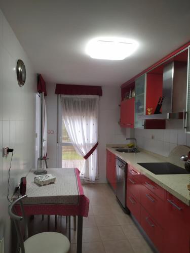 ArenalApartamento Casa Labaro, junto al Parque de Cabárceno的厨房配有红色橱柜、桌子和窗户