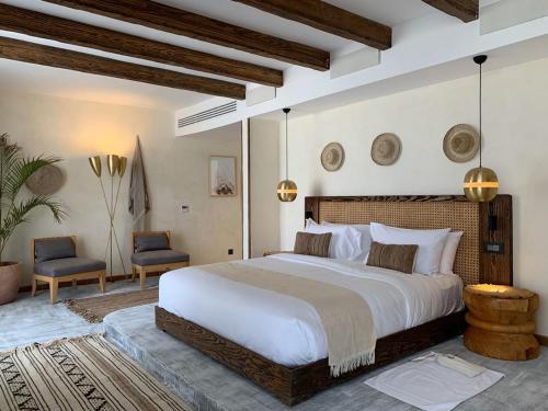 阿莱曼Le Sidi - A TLT Signature Hotel的一间卧室配有一张大床和两把椅子