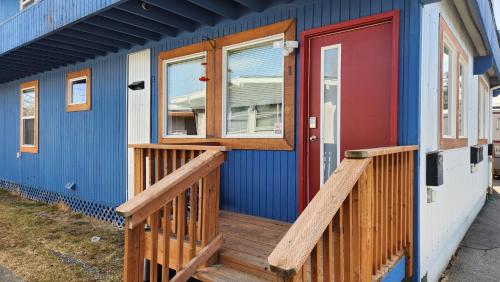 安克雷奇Nightshade BnB的蓝色的房子,设有木门廊和红色的门