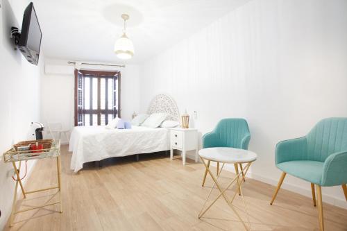 科尔多瓦Altabib Riad的一间白色卧室,配有一张床和两把椅子