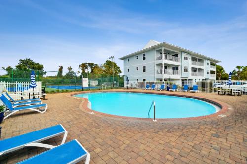 锡格罗夫海滩Beachside Villas by Panhandle Getaways的一座带蓝色椅子的游泳池和一座建筑