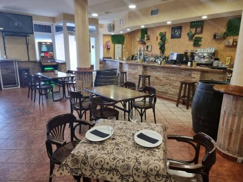 La PueblanuevaHostal Restaurante CASA FRAN的一间带桌椅的餐厅和一间酒吧