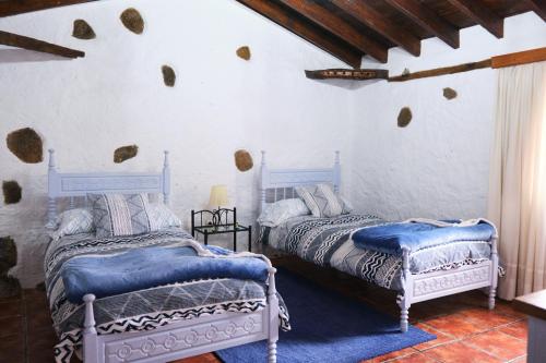 San Juan de la RamblaCasa Rural Felipe Luis的白色墙壁客房的两张床