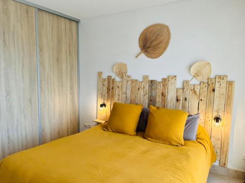 阿雅克修Appartement VAIANA avec piscine en bord de mer的一间卧室配有一张黄色的床和木制床头板
