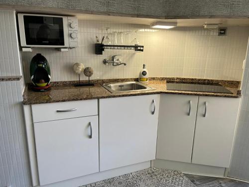 拉皮内达La Pineda playa的白色的厨房配有水槽和微波炉