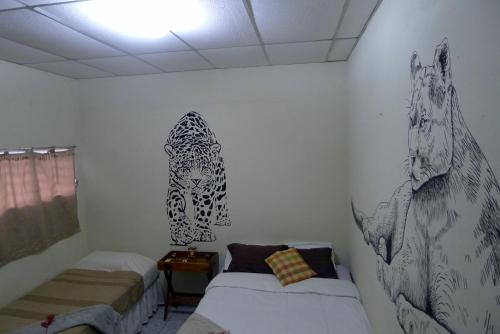 马塔加尔帕Matagalpa Tours Guest House的一间卧室设有两张床,墙上挂有绘画作品