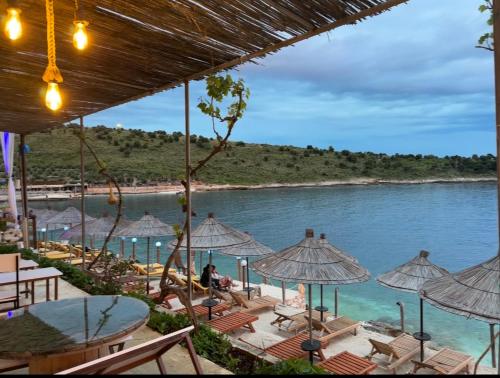 萨兰达Villa Xhefri 2的享有带椅子和遮阳伞的海滩美景