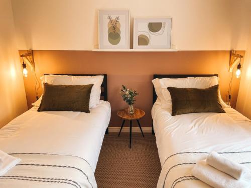 纽波特Hollybush Apartment, by Solace Stays的小型客房配有两张床和一张桌子。