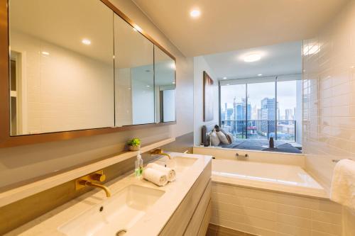 布里斯班Multi Million River View 3BD Penthouse at SouthBank的一间带水槽和浴缸的浴室以及窗户。