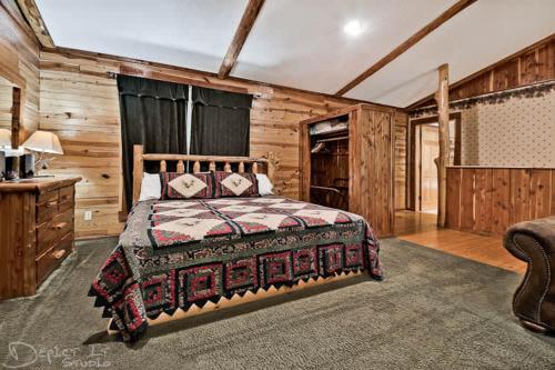 尤里卡斯普林斯Secluded Cabin Pool WiFi smart TVs Beaver lake的卧室配有一张床铺,位于带木墙的房间内