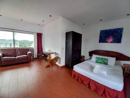 圣萨尔瓦多La Zona Hostel的一间卧室配有一张床、一张沙发和一张桌子