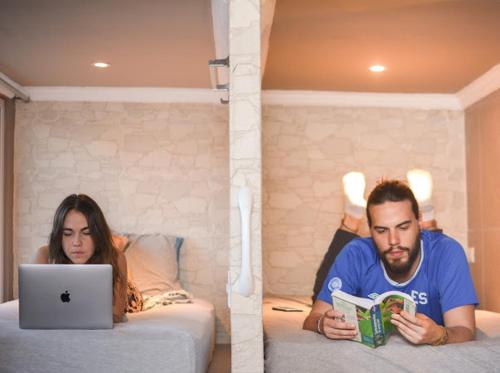 圣萨尔瓦多La Zona Hostel的男人和女人躺在床上,手提电脑