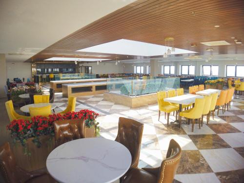 岘港ATP Galaxy Hotel & Apartment的一间带桌子和黄色椅子的餐厅和一间自助餐厅