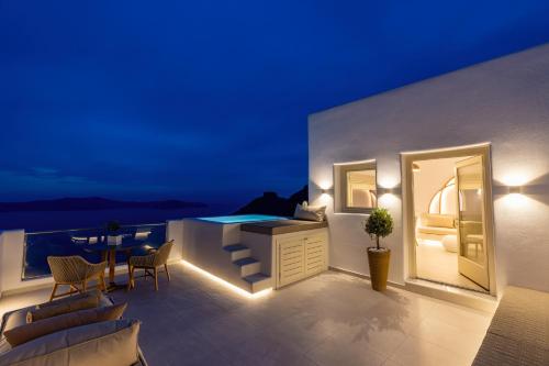 菲罗斯特法尼Santorini View Studios - Firostefani Caldera的阳台配有浴缸和桌椅。