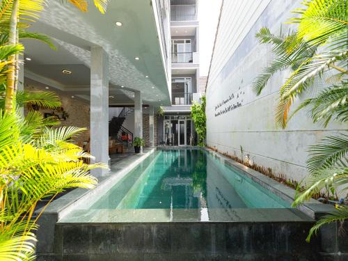 会安HA Hero Hoian Pool House的棕榈树建筑中间的游泳池