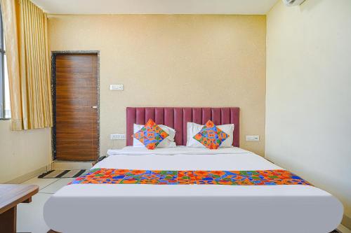 印多尔FabHotel Sukh Vilas的一间卧室配有一张大床和红色床头板
