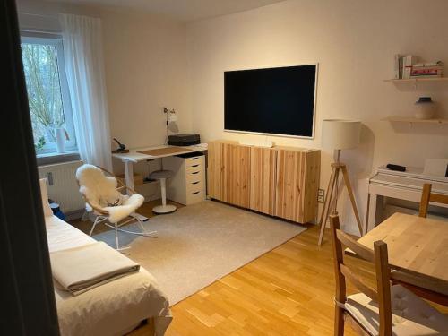 布伦瑞克Geschmackvoll eingerichtete Wohnung in Braunschweig的客厅配有书桌和墙上的电视