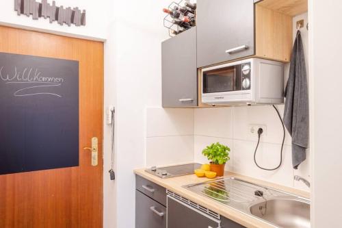 慕尼黑Stilvolles Appartement im lässigsten Viertel的一间带水槽和微波炉的小厨房