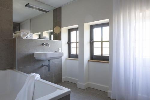 里昂富维耶酒店的带浴缸、水槽和窗户的浴室