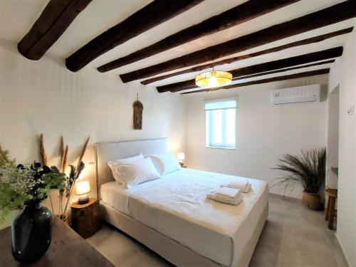 安德罗斯Spiti Sea View Neoclassical House in Stenies的一间带白色床铺的卧室,位于带木制天花板的客房内。
