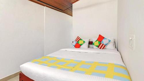 马迪凯里Westernghats Homestay的一间白色的小卧室,配有带色彩缤纷枕头的床