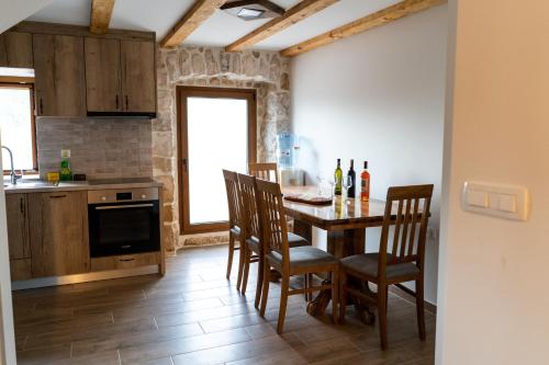 柳布什基Kamena Kuća Vegar的厨房配有木桌、椅子和柜台