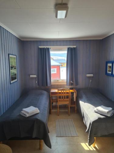 贝勒沃格Berlevåg Motell AS的客房设有两张床、一张桌子和一扇窗户。