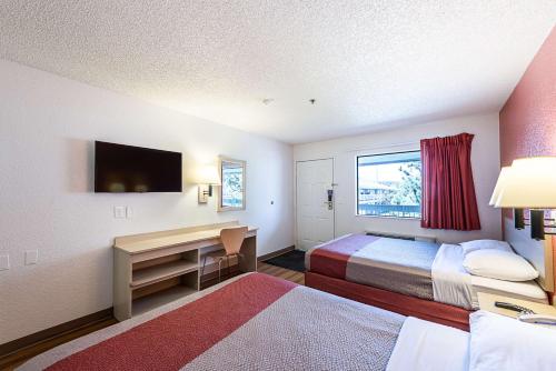 里诺里诺机场6号汽车旅馆 - 斯帕克斯的酒店客房设有两张床、一张桌子和一台电视。
