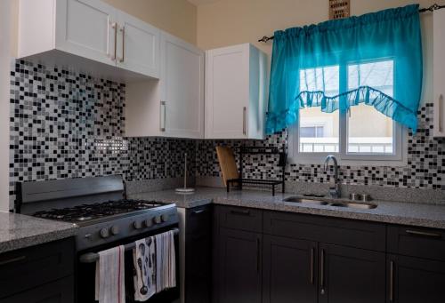 卢西Hamilton @ Oceanpointe a serene 2bed 2 bath Villa的厨房配有炉灶、水槽和窗户。