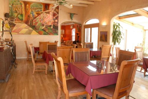 阿尔伯克基Casas de Suenos Old Town Historic Inn, Ascend Hotel Collection的一间带桌椅和绘画的用餐室