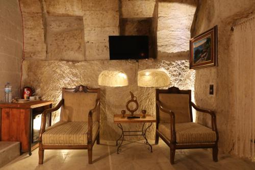 阿瓦诺斯Atax Cave House的一间设有两把椅子、一张桌子和一台电视的房间
