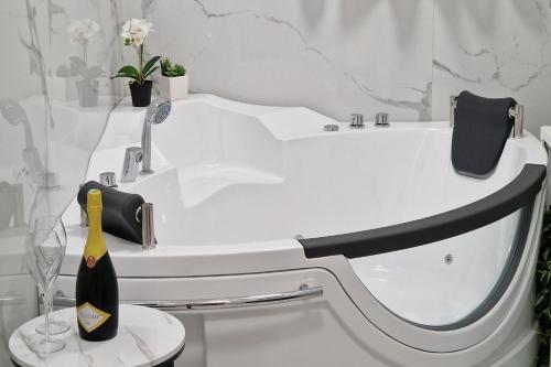 斯韦蒂·斯特凡Montesan Luxury Apartment的白色浴缸,凳子上备有一瓶香槟